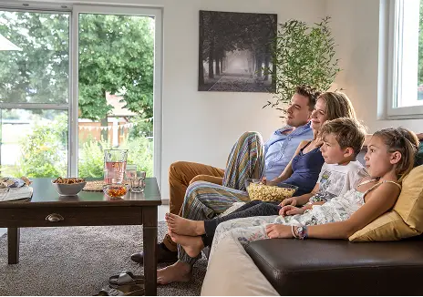 Fliegengitter an der Terrassentür für entspanntes Wohnen Familie sitzt gemeinsam im Wohnzimmer neben einer Terrassentür mit Fliegengitter und Blick in den Garten